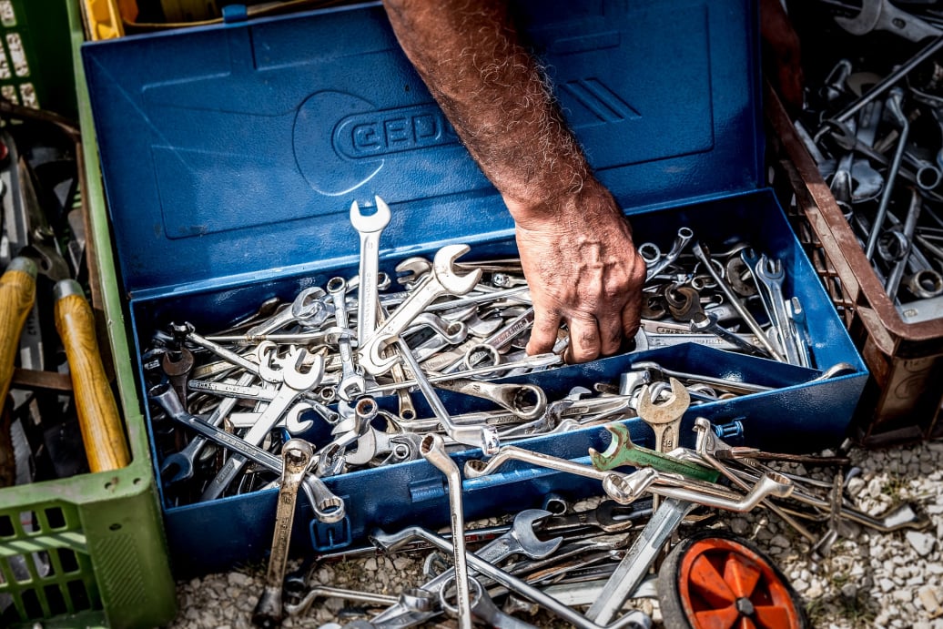 A hand reaching into a toolbox to extract a tool.