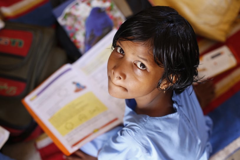 A school child holding an open book.