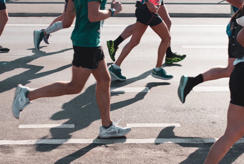 A photograph of the legs of a number of people running a marathon.